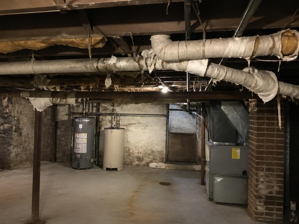 Basement with aged pipe insulation wrap before asbestos abatement