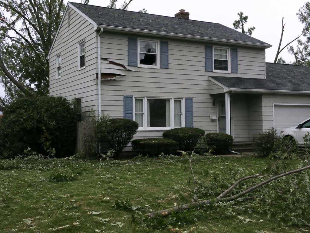 Fallen tree and damaged siding on a Central Indiana home before storm repair