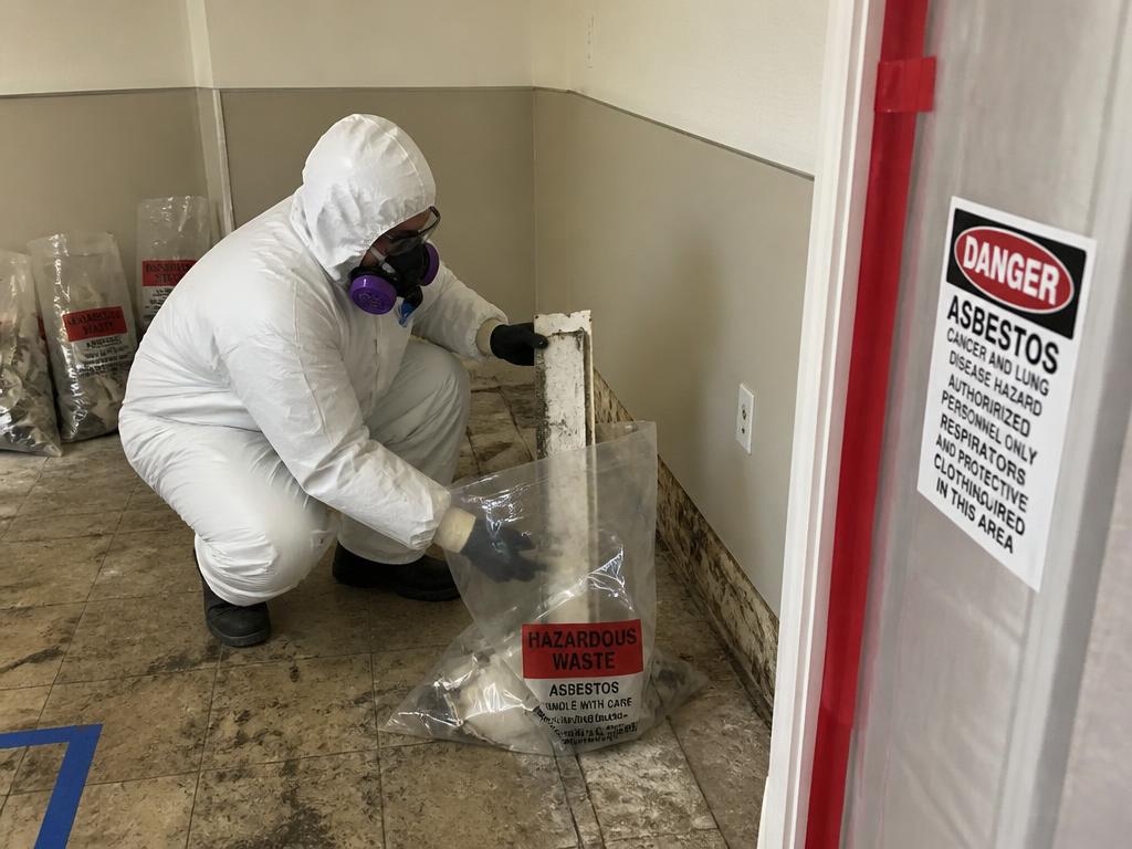 Licensed worker removing asbestos containing material inside containment