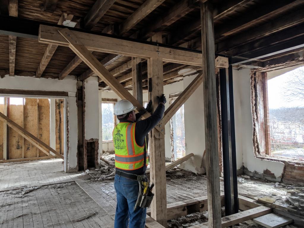 Contractor installing temporary structural bracing inside a damaged building