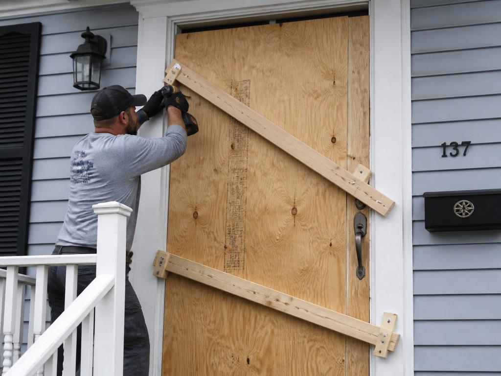 Worker securing a damaged entry door with plywood and bracing