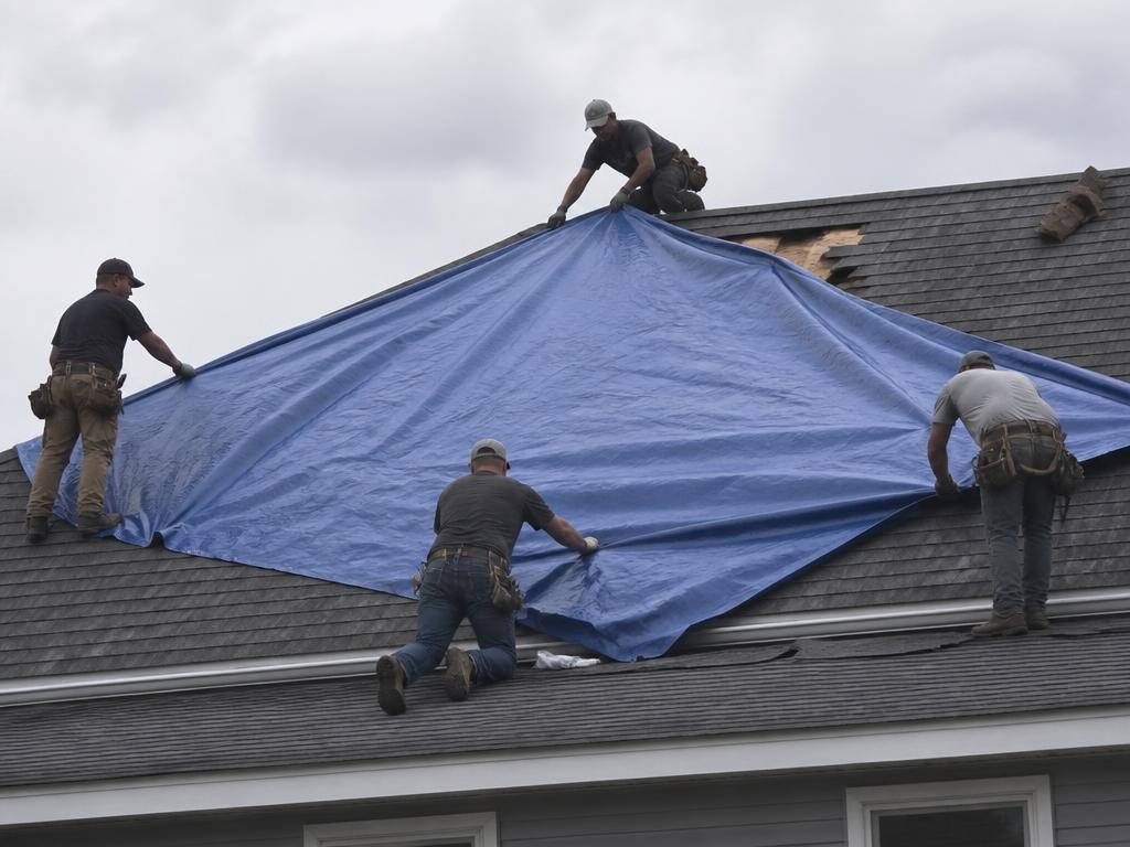 Crew installing a tarp over a damaged roof section