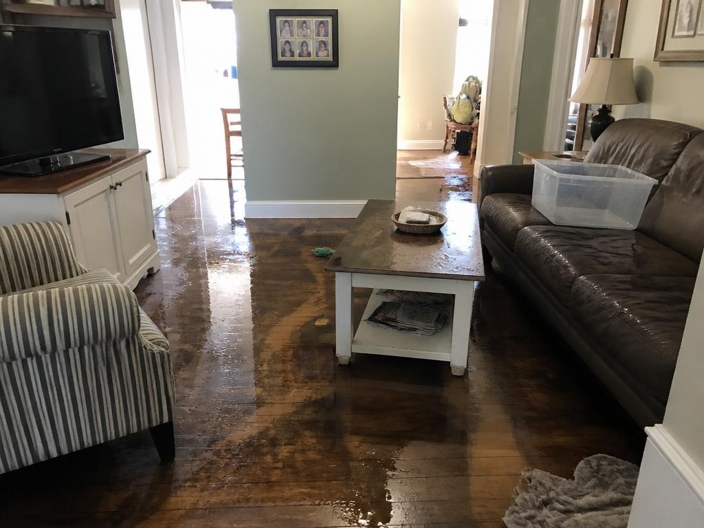 Living room with water damaged hardwood flooring after an upstairs leak